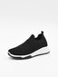 Zapatilla slip-on negra de punto knit con suela blanca y detalles en relieve en el tejido, sin cordones.