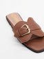 Flat brown sandals with gold buckle and square toe.