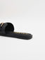 Sandalias negras planas con hebilla dorada y puntera cuadrada.