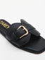 Sandalias negras planas con hebilla dorada y puntera cuadrada.