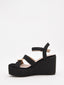 Sandalias de cuña alta en rafia negra y beige con plataforma y tiras cruzadas. Modernas, cómodas y versátiles.