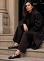 Merceditas de mujer AZAREY en color negro con tira de hebilla y detalle de tachuelas metálicas, diseñadas para aportar un toque elegante y actual a los looks de temporada. La imagen muestra el calzado combinado con un estilismo sofisticado en tonos oscuros, resaltando su silueta femenina, cómoda y versátil. Un zapato plano ideal para diario, oficina o conjuntos urbanos con un aire refinado.